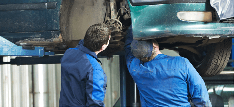 Mechanics inspecting car suspension system for repair in Elgin, IL.