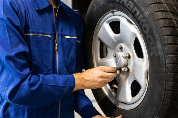 Technician inspecting car tire for seasonal auto maintenance.