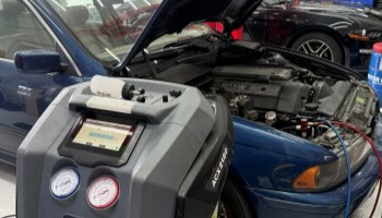 Automotive diagnostic machine testing a blue sports car engine.