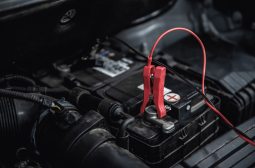 Car battery with jumper cables connected for electrical service.