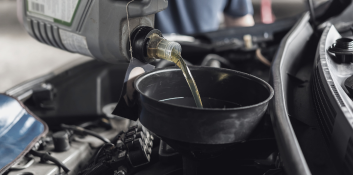 Engine oil being poured into a car engine during maintenance.