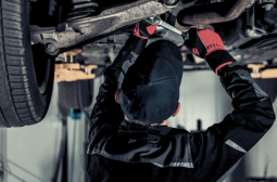 Technician performing vehicle maintenance under the car.