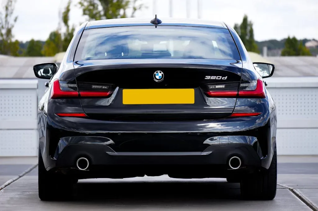 Rear view of a black BMW 320d in a parking lot, showcasing clean exhaust system.