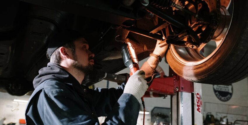 Skilled technician performing mechanical repairs on a car