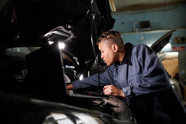 Auto mechanic inspecting engine under the hood for check engine light issues.