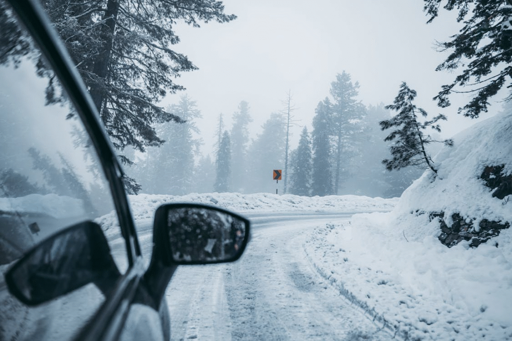 Snow-covered mountain road with icy curves and a vehicle navigating safely.