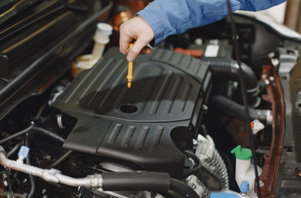 Engine oil dipstick being checked for fluid leaks and color indication.