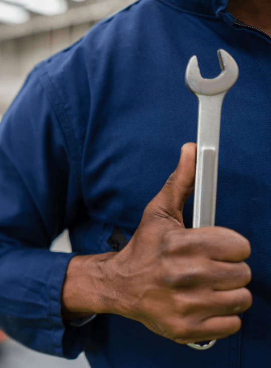 Technician holding a wrench at Northville Auto INC for vehicle repair services.