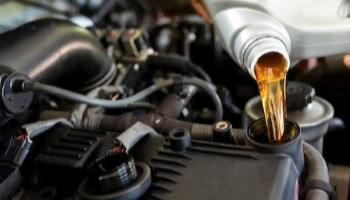 Engine oil being poured into a car engine during maintenance.