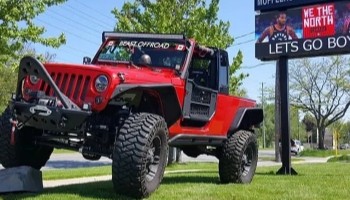 Red Jeep Wrangler off-road vehicle on grass at Noyzboyz Performance.