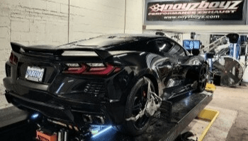 Black sports car on dynamometer for performance tuning at Noyzboyz.