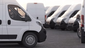 Fleet of white commercial vans parked outdoors, showcasing Noyzboyz Performance vehicle services.