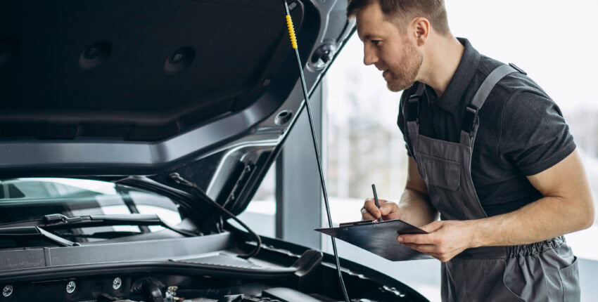 Mobile auto repair technician inspecting car engine during oil change service.