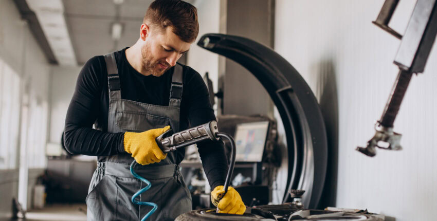 Skilled auto repair technician performing maintenance on a vehicle in a garage.