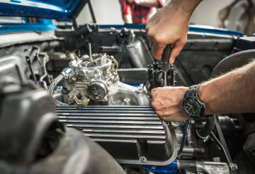 Engine repair technician working on car engine at One Stop Lube.