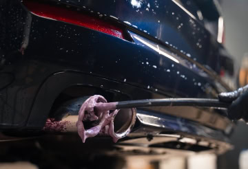 Auto exhaust pipe being cleaned at One Stop Lube.