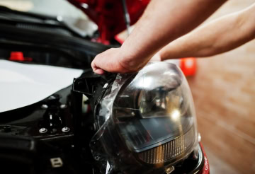 Auto lube service being performed on a vehicle's headlight and engine area.