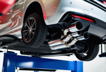 Close-up of a car's exhaust pipes on a vehicle lifted for maintenance.