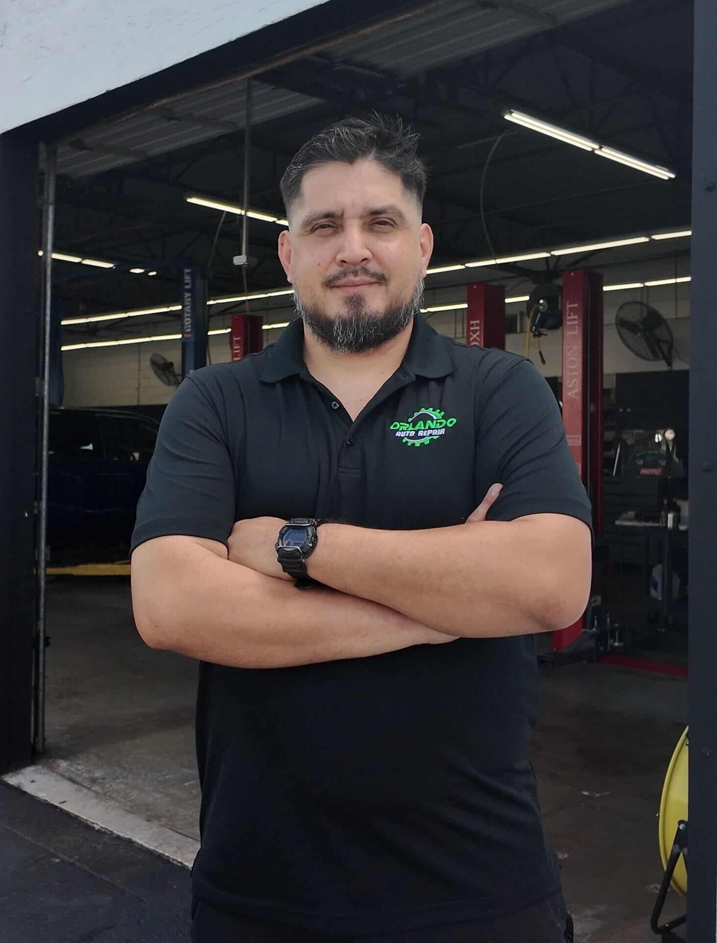 Skilled auto technician at Orlando Auto Repair with arms crossed in the workshop.