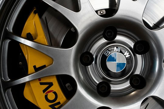 BMW alloy wheel with yellow brake caliper and M Performance branding.