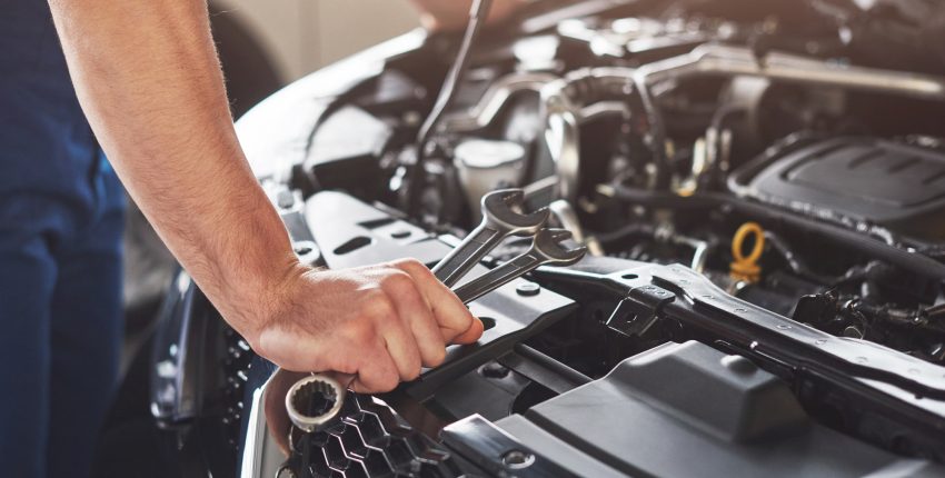 Mechanic inspecting car engine for early issues during routine maintenance in Orlando.