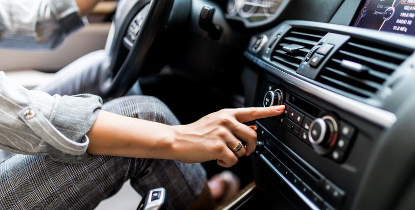 Person adjusting car air conditioning and heating system for optimal comfort.