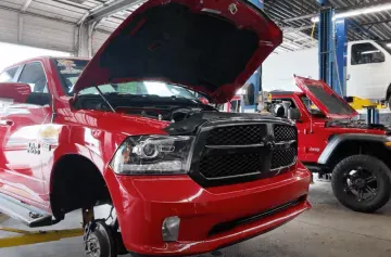 Auto repair shop with red trucks and open hoods, vehicle maintenance and engine service.