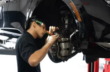 Auto repair technician inspecting brake system on a vehicle.