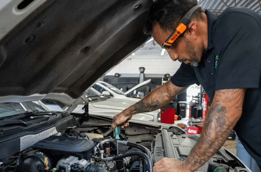 Orlando auto repair technician inspecting car engine under the hood.