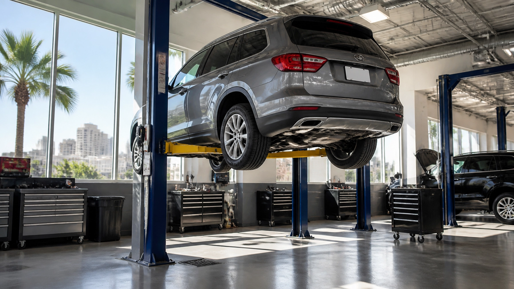 Auto repair shop with a gray SUV elevated on a hydraulic lift, inside a modern, well-lit garage in O.