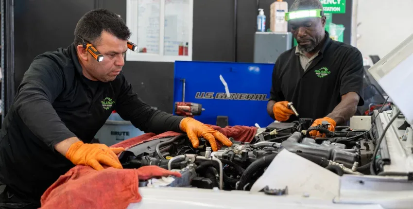 Mechanics working on car engine at Orlando Auto Repair shop.