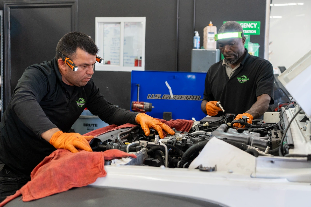 Mechanics working on car engine at Orlando Auto Repair shop.