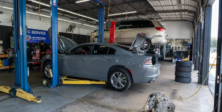 Auto repair shop with cars on lifts and engine work in progress.