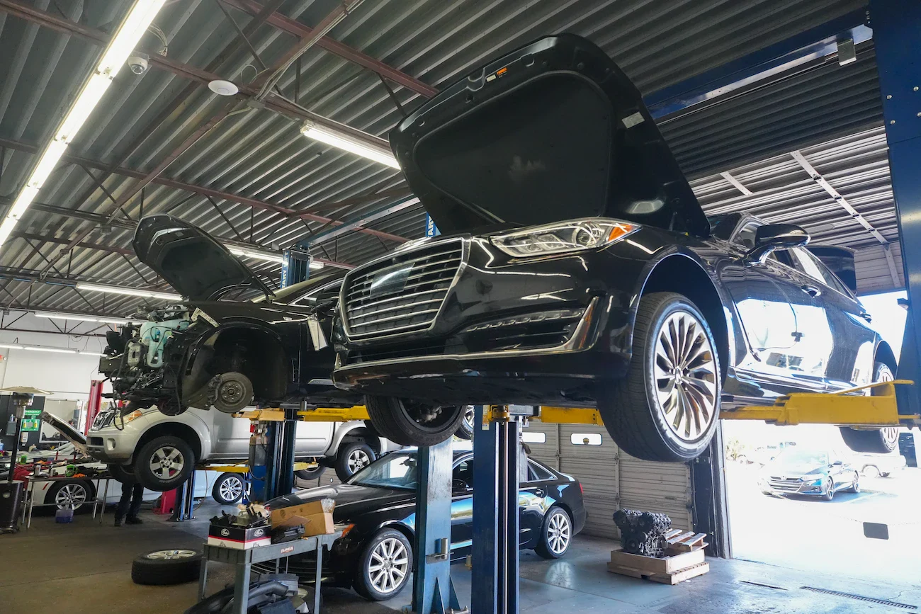 Black sedan on lift with open hood at Orlando Auto Repair.