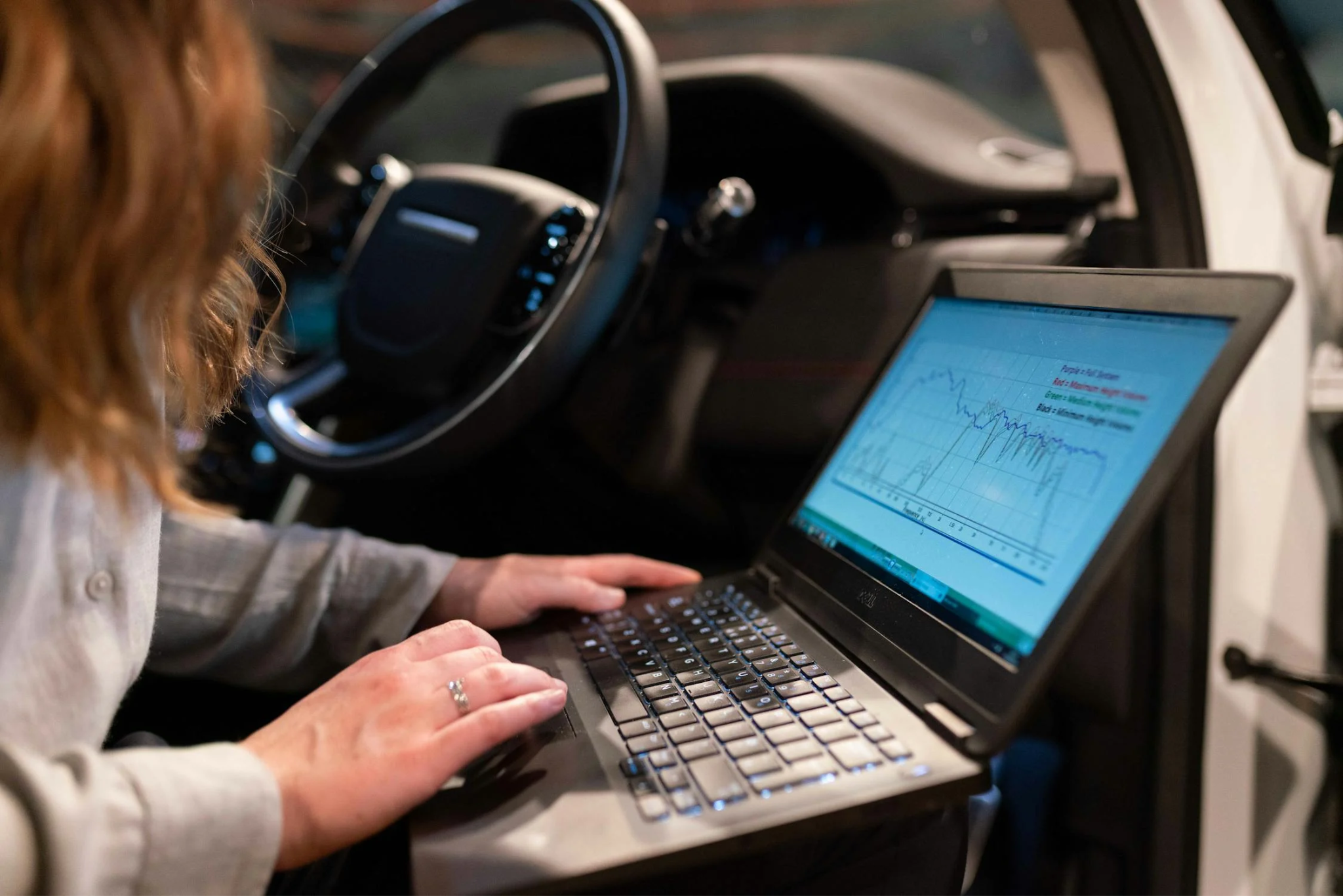 Technician using diagnostic tools on vehicle's onboard computer system.