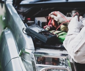 Technician testing car battery with diagnostic tools at Parney’s Car Care.