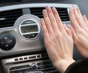 Technician inspecting car air conditioning system for optimal performance.