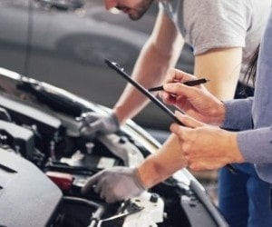 Automotive technician performing quick lube maintenance on a vehicle engine.