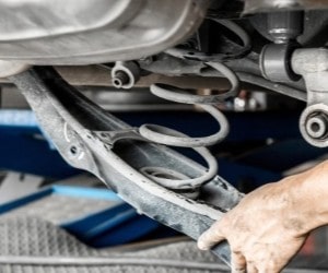 Suspension repair service showing a mechanic working on a vehicle's suspension system.
