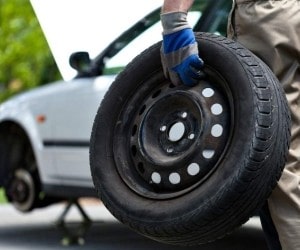 Technician holding a car tire for replacement at Parney’s Car Care.