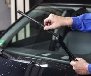 Hand replacing windshield wiper on a vehicle during quick lube service at Parney’s Car Care.