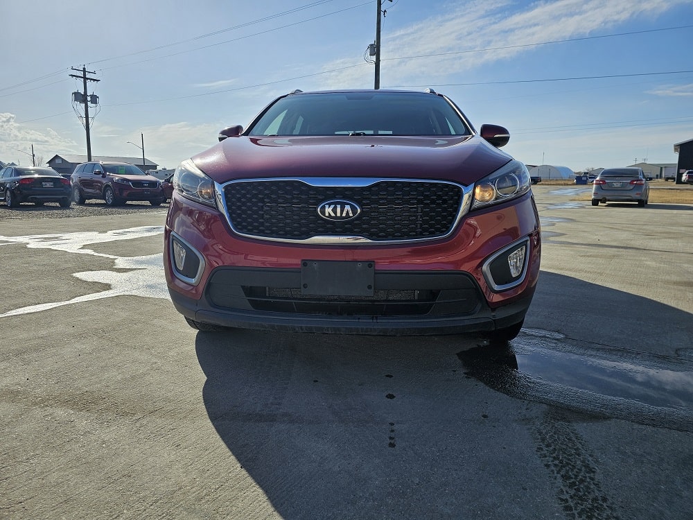 Red Kia SUV parked at Pembina Valley auto dealership for vehicle sales.