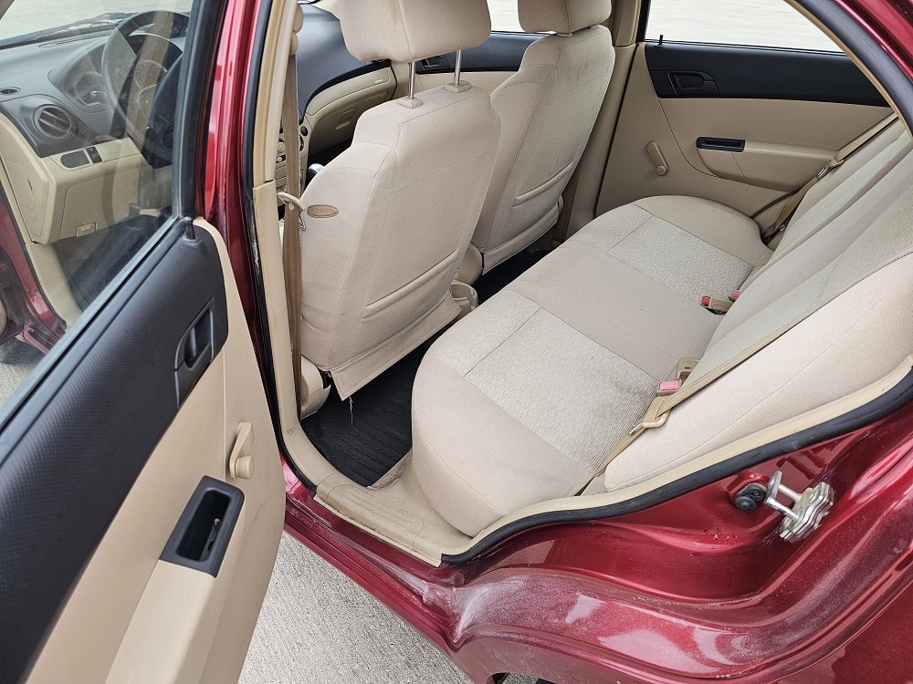 Interior view of a compact sedan showing beige fabric seats and rear passenger area.