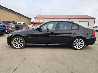 Used Black BMW sedan parked outside Pembina Valley Auto dealership in Manitoba.