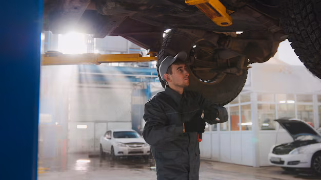 Mechanic checking car wheel underneath vehicle in a garage