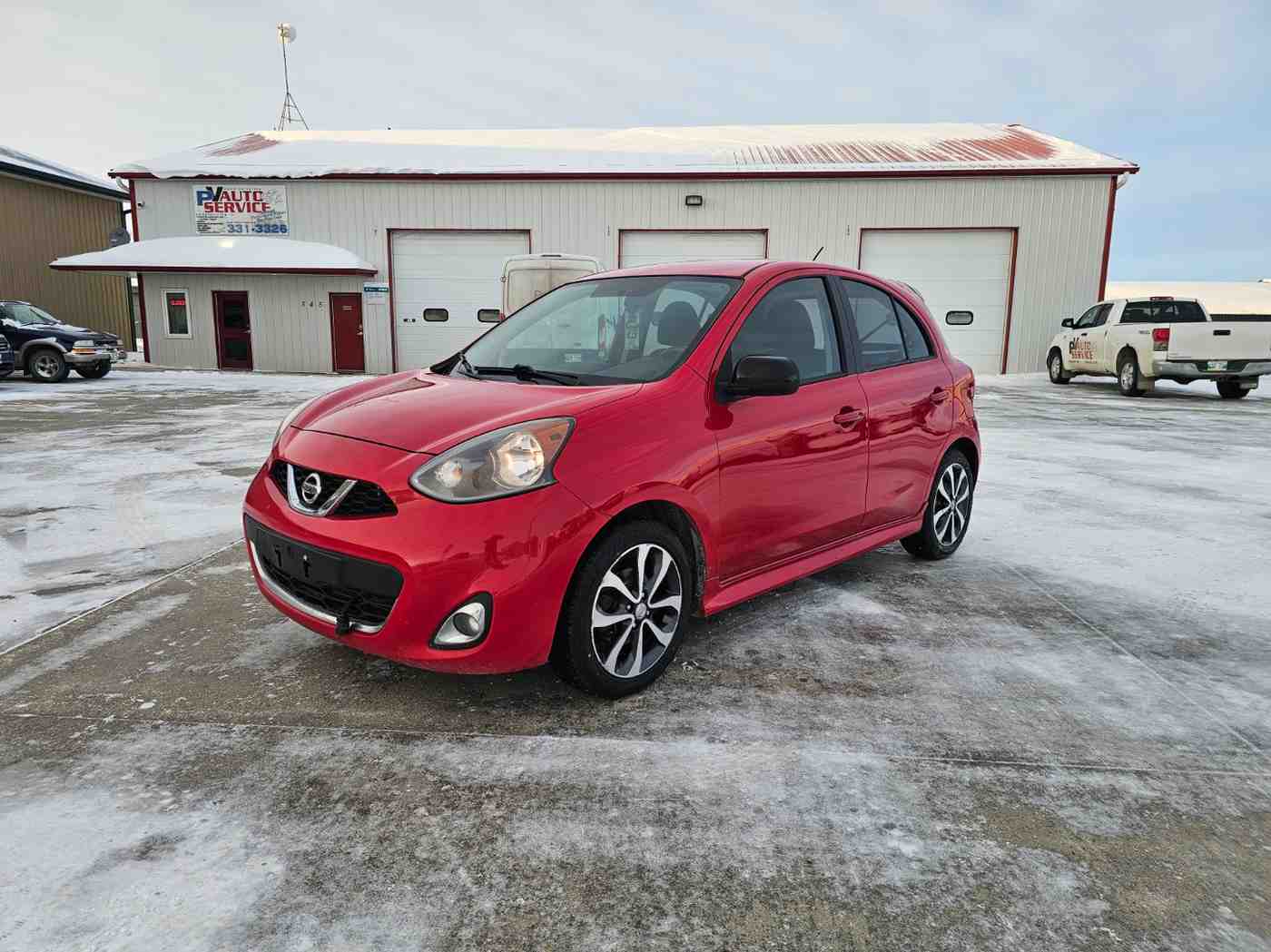 Red Mazda hatchback parked in Pembina Valley auto lot during winter.