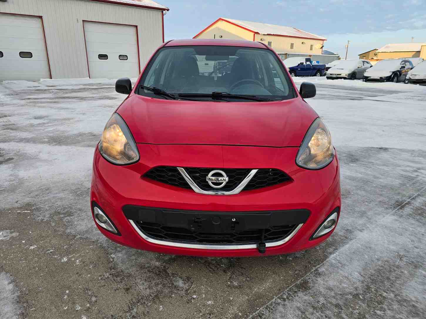 Red Nissan compact car parked outdoors in Pembina Valley, Manitoba.