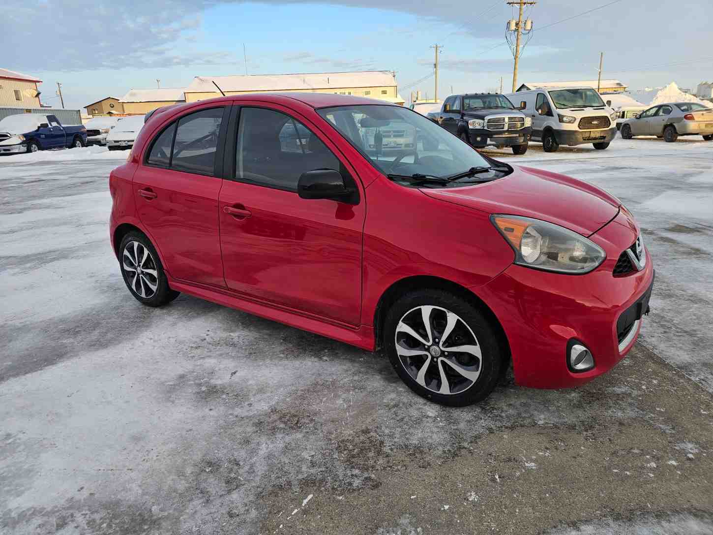 Red Nissan hatchback in Pembina Valley auto dealership lot.