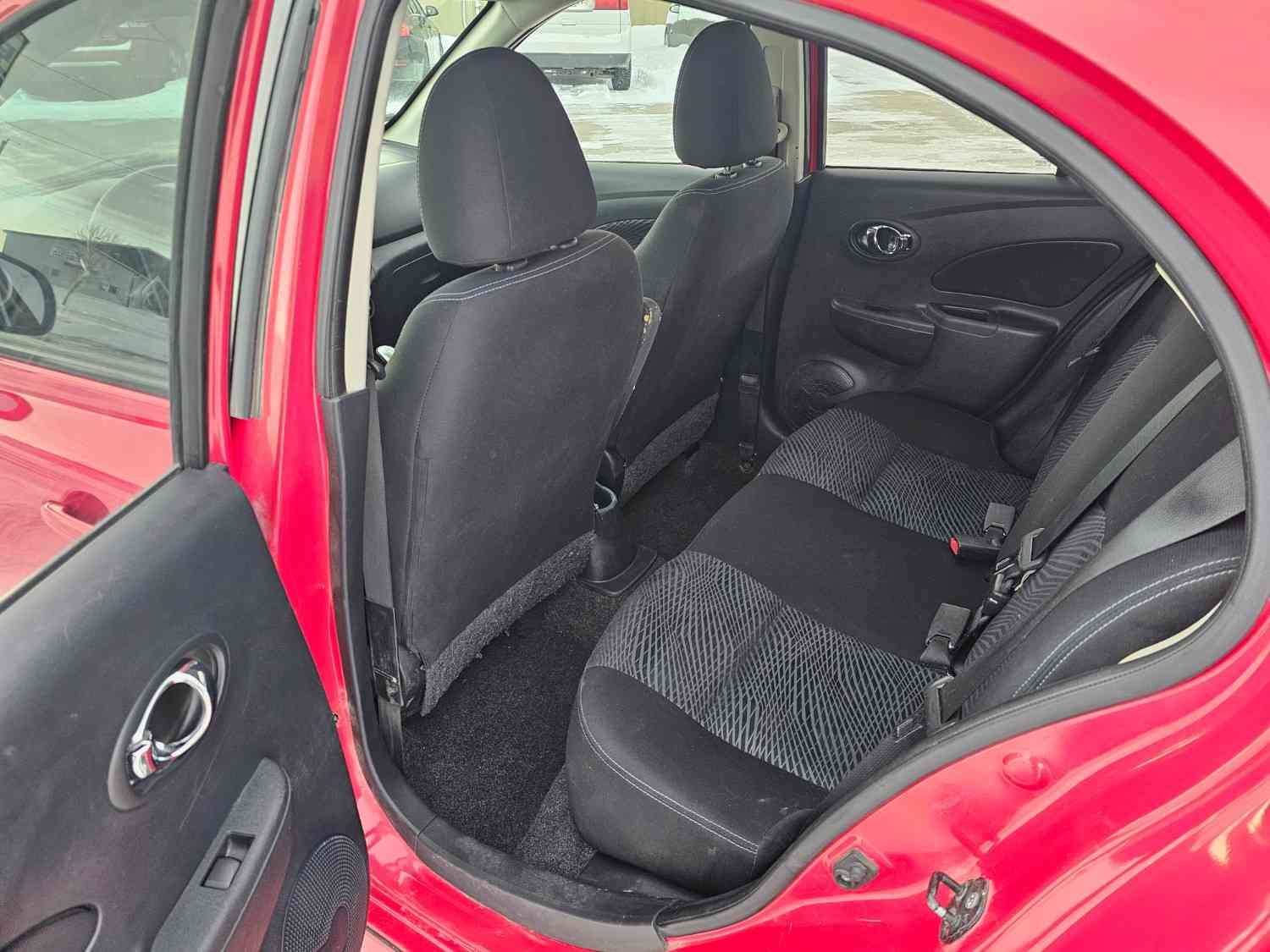 Interior view of a compact red vehicle showing the back seats and door panel.