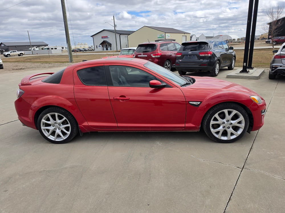 Red Mazda sedan, stylish and well-maintained, parked at Pembina Valley Auto dealership.